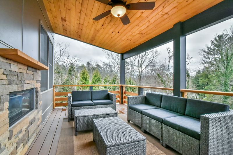 A porch with a lot of furniture and a ceiling fan.