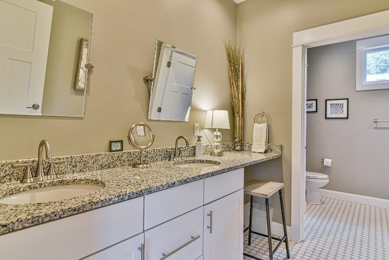 A bathroom with two sinks, a mirror, and a toilet.