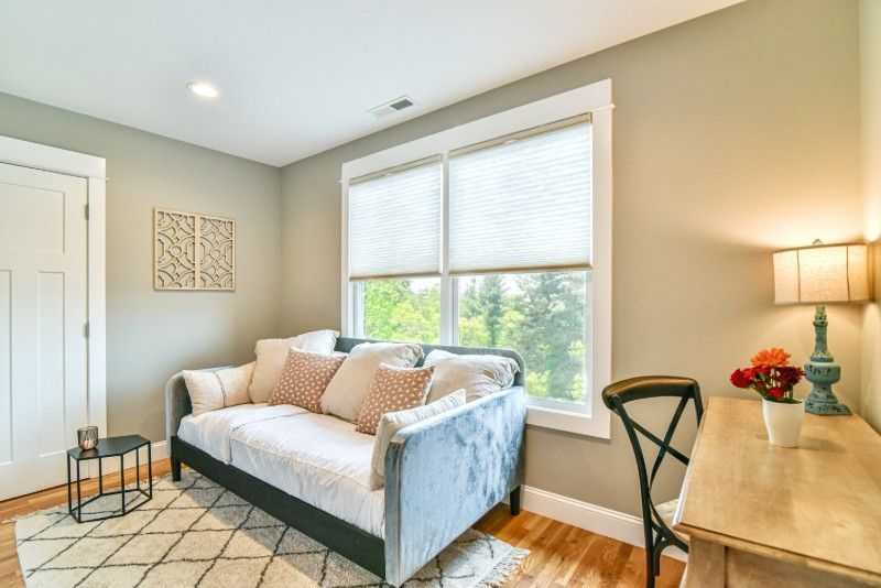 A living room with a couch, desk, lamp, and window.