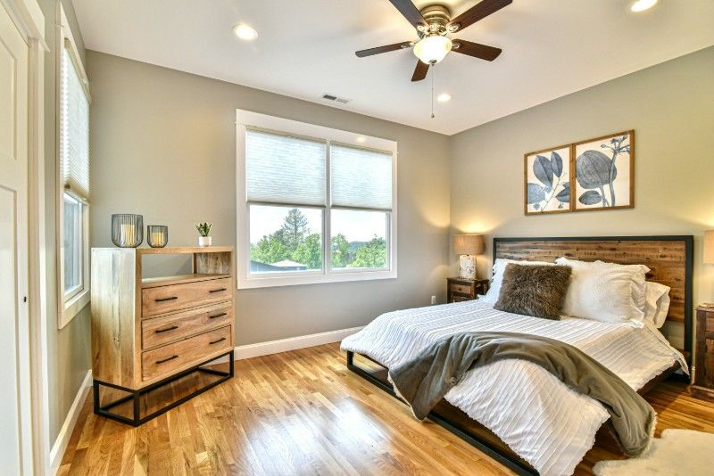 A bedroom with a bed, dresser, nightstand, and ceiling fan.