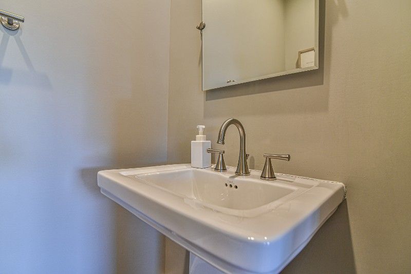 A bathroom with a sink, mirror, and soap dispenser.