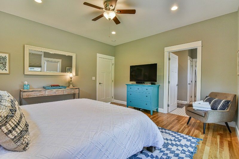 A bedroom with a bed, dresser, chair, and television.