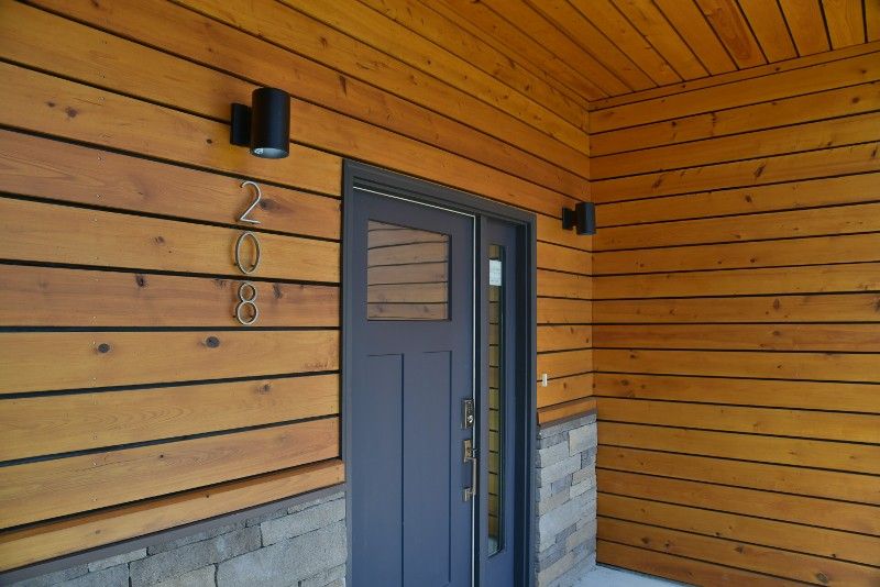 A wooden house with a black door and a light on the side.