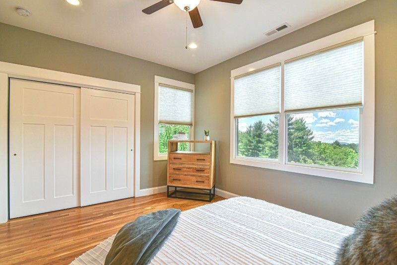A bedroom with a bed, dresser, and ceiling fan.