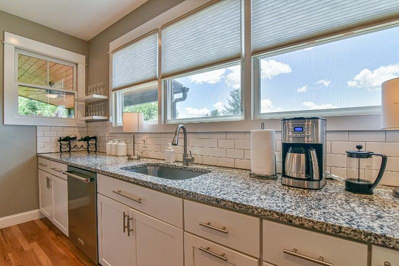 A kitchen with granite counter tops, a sink, a dishwasher, and a coffee maker.