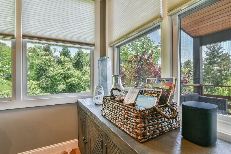 A wicker basket filled with books is sitting on a counter next to a window.