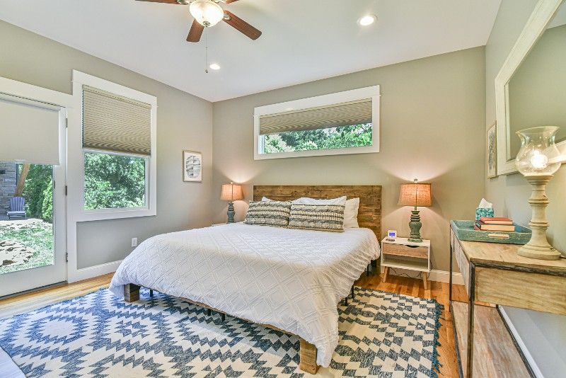 A bedroom with a bed, nightstand, rug, and ceiling fan.