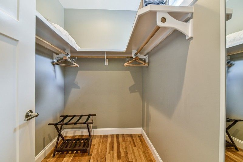 A walk-in closet with a suitcase rack and a mirror.