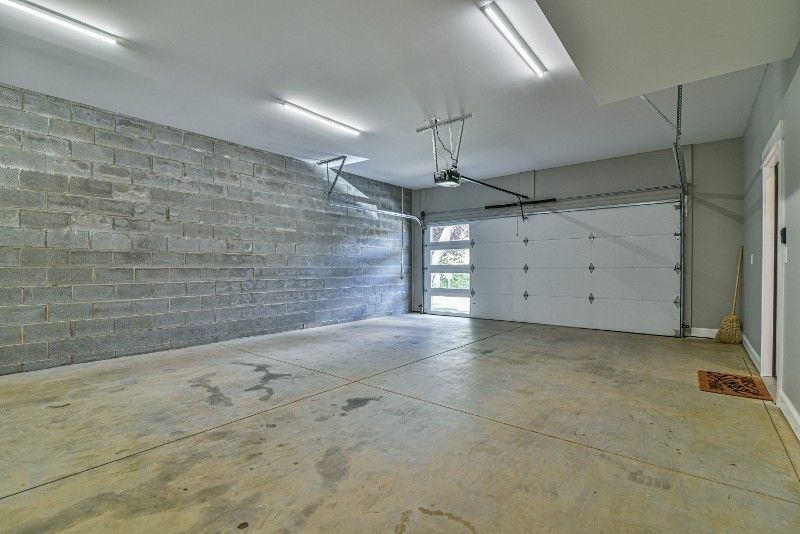 An empty garage with a white garage door and a brick wall.