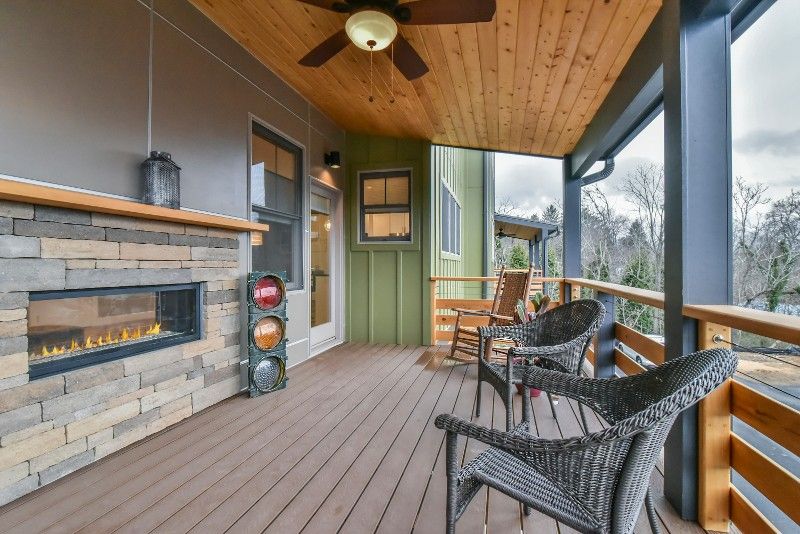 A porch with chairs , a fireplace and a ceiling fan.