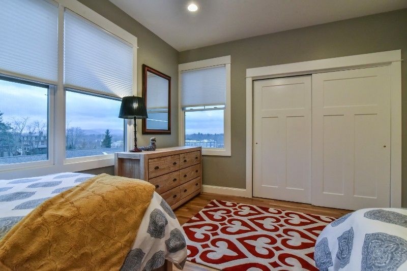 A bedroom with two beds , a dresser , and a rug.