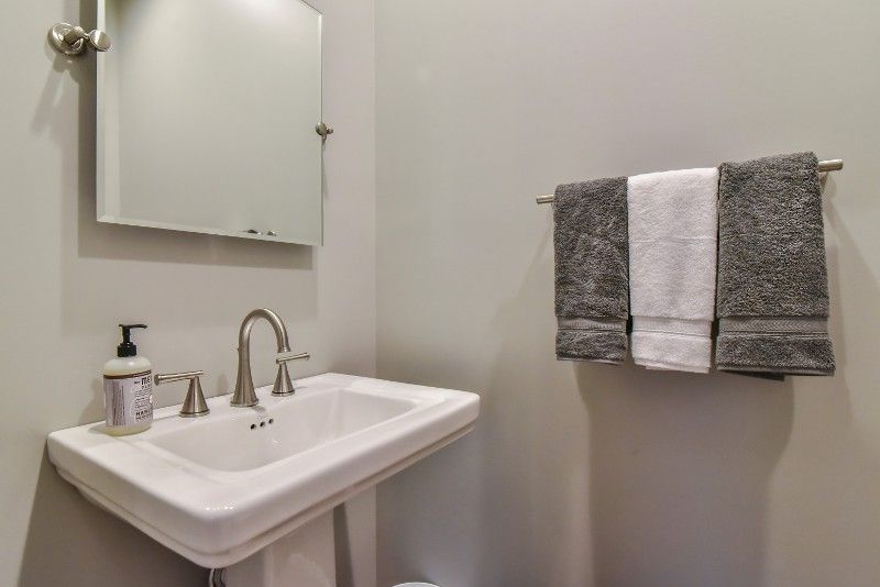 A bathroom with a sink , mirror and towels hanging on the wall.