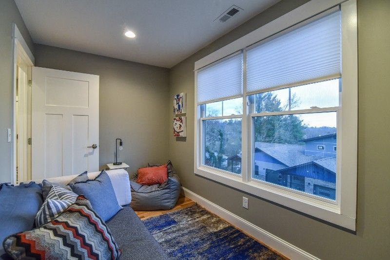 A living room with a couch , bean bag chair , and two windows.