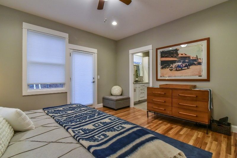 A bedroom with a bed , dresser , chair and a picture on the wall.