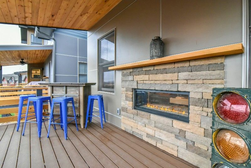 A deck with a fireplace and stools on it.
