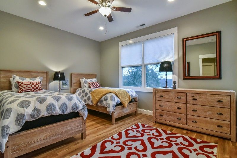 A bedroom with two beds , a dresser , a mirror and a ceiling fan.