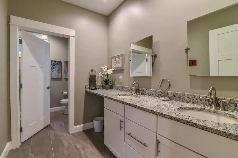 A bathroom with two sinks , a mirror and a toilet.