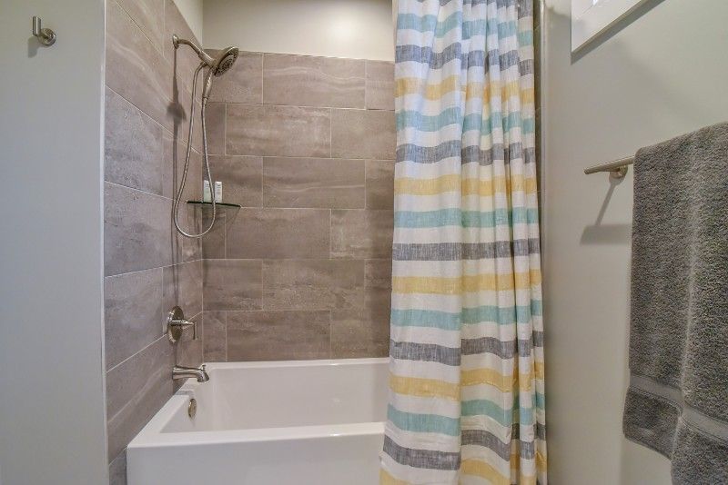 A bathroom with a bathtub , shower , and striped shower curtain.