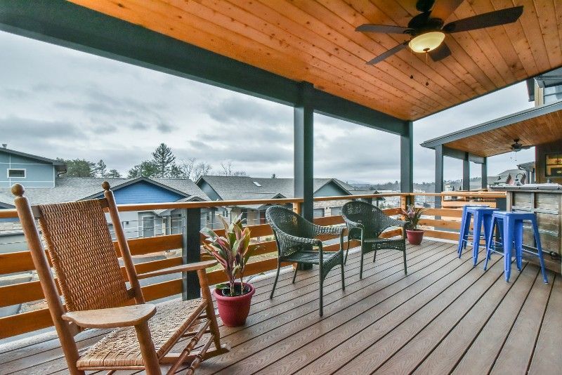 A wooden deck with rocking chairs and a ceiling fan.