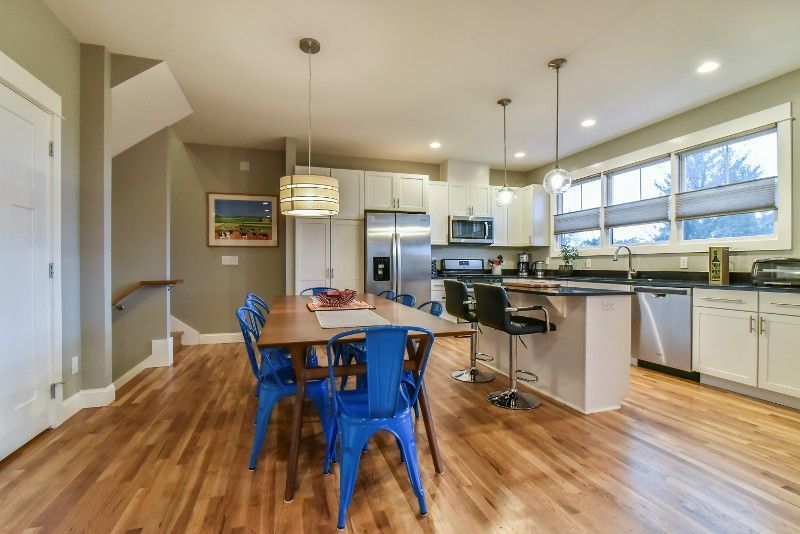 A kitchen and dining room in a house with hardwood floors and stainless steel appliances.