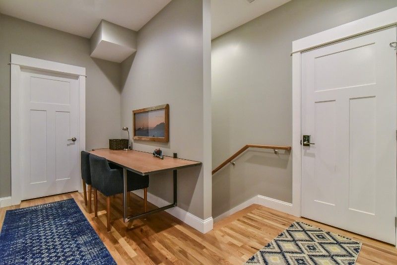 A hallway with a desk and chairs in a house.