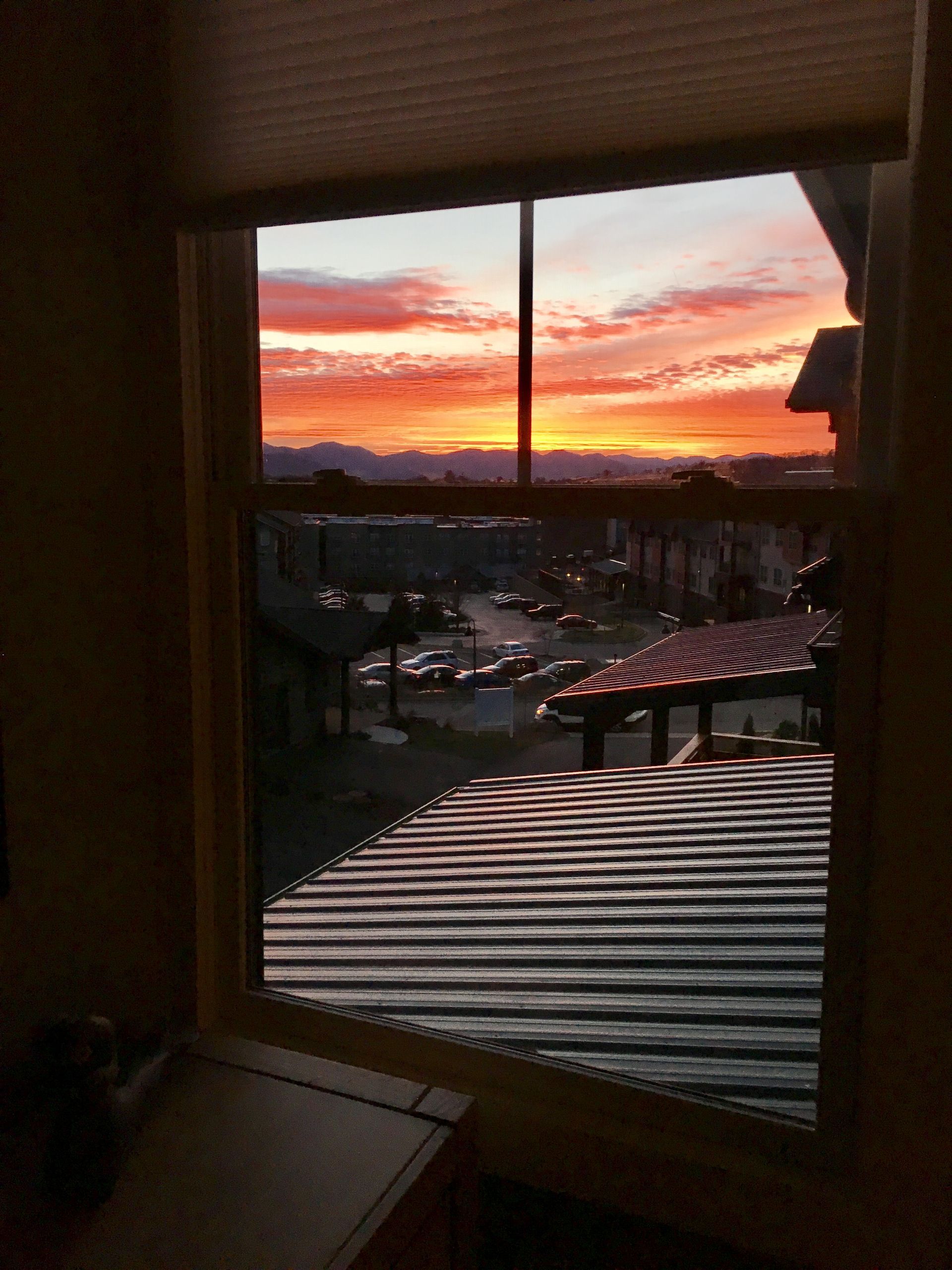 A window with a view of a sunset in the background.