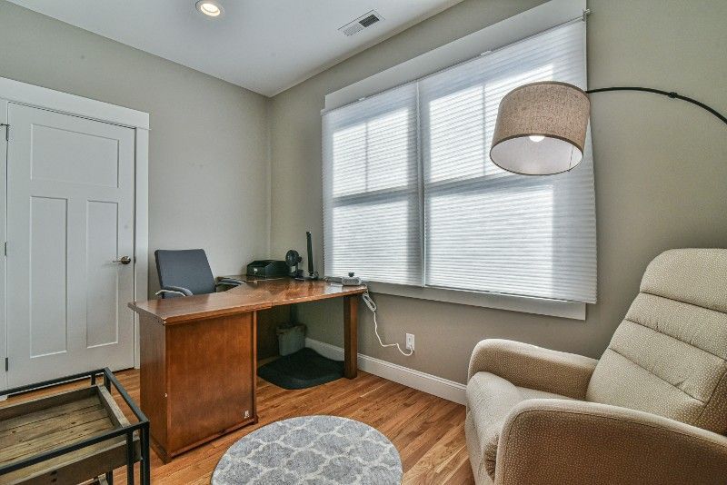 A home office with a desk , chair , lamp and window.