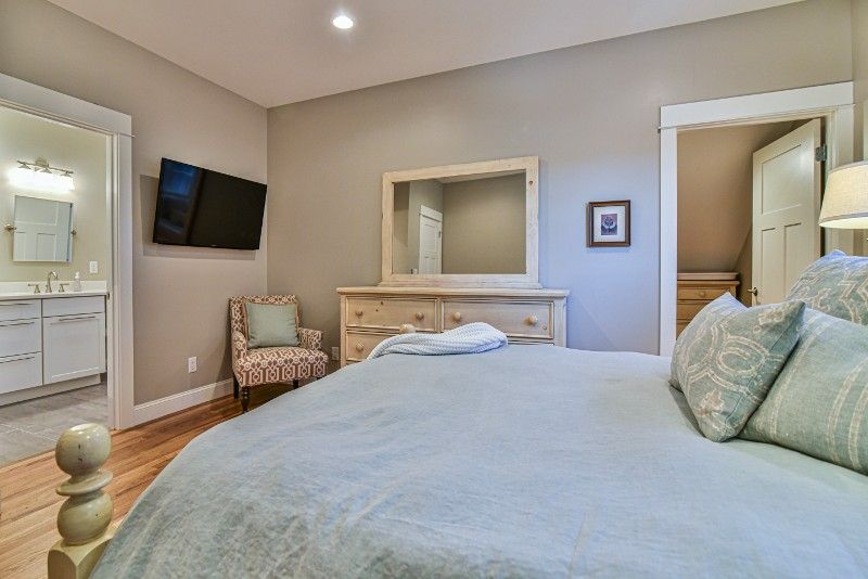 A bedroom with a king size bed , dresser , mirror and television.