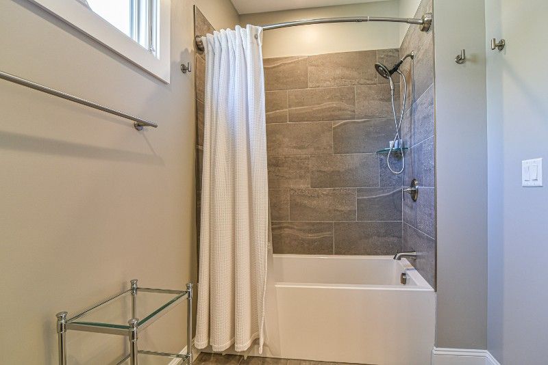 A bathroom with a tub , shower , and window.