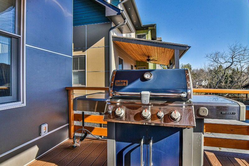 A grill is sitting on a deck next to a house.