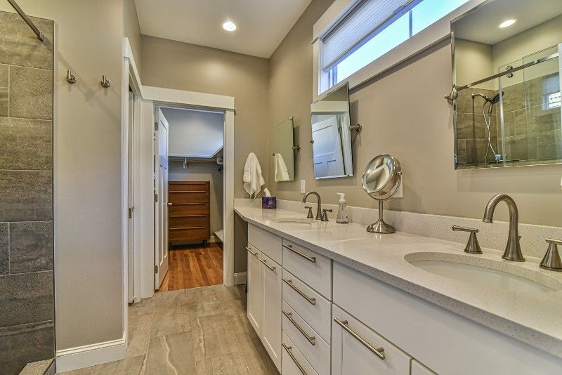 A bathroom with two sinks , a mirror and a walk in shower.
