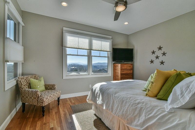 A bedroom with a bed , chair , television and ceiling fan.