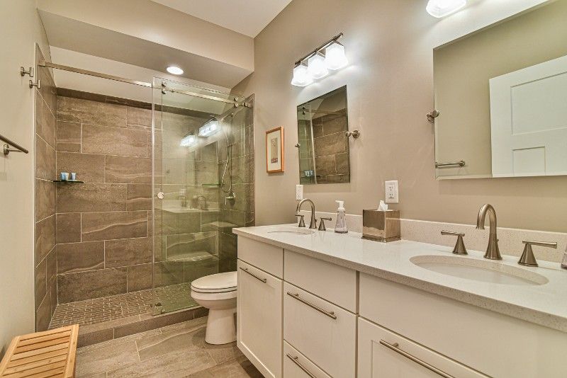 A bathroom with a toilet , sink , mirror and walk in shower.