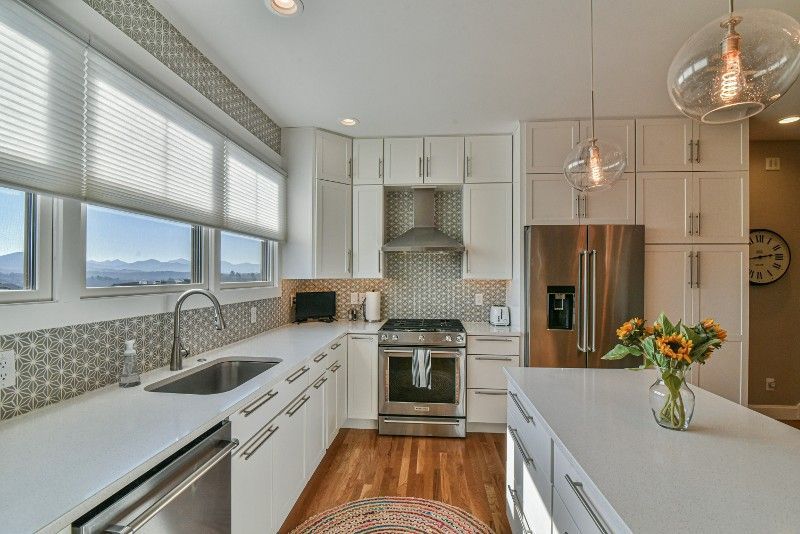 A kitchen with white cabinets , stainless steel appliances , a sink , and a refrigerator.
