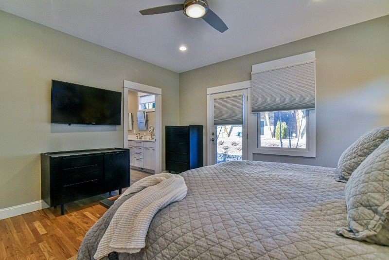 A bedroom with a bed , television , dresser and ceiling fan.