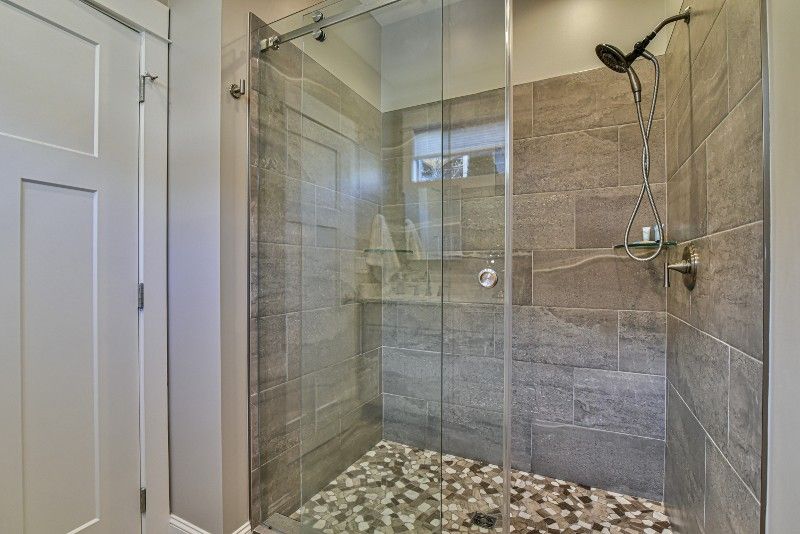 A bathroom with a walk in shower with a glass door.