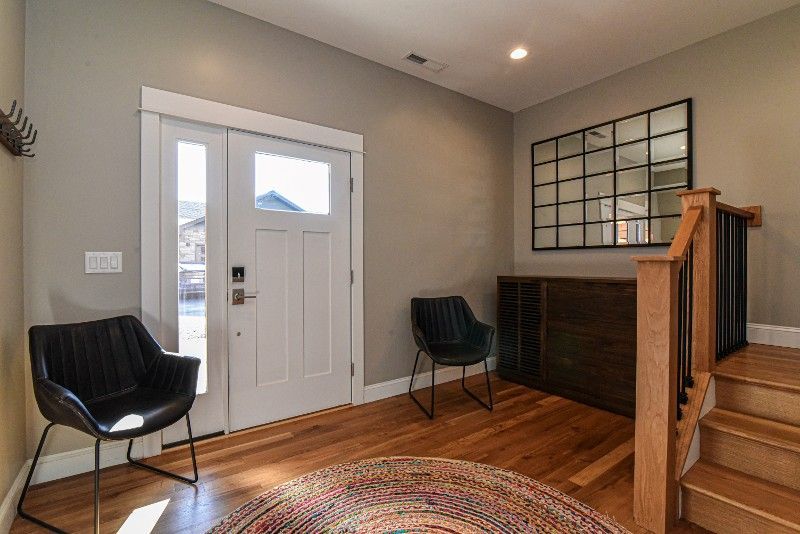 A hallway with two chairs and stairs in a house.