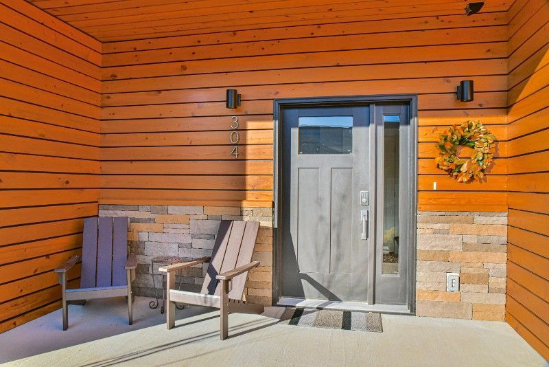 A porch with chairs and a wreath on the door of a house.