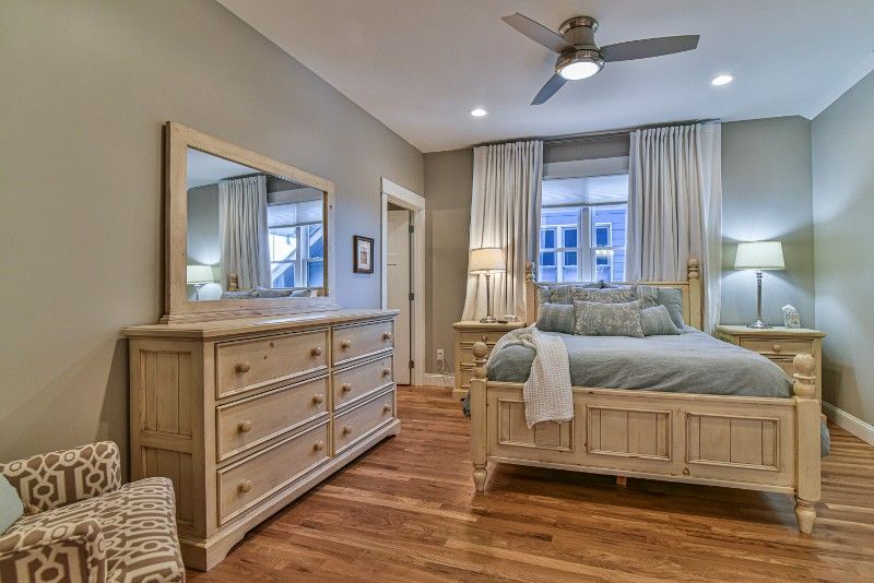 A bedroom with a bed , dresser , mirror and ceiling fan.