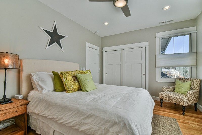 A bedroom with a bed , chair , nightstand and ceiling fan.