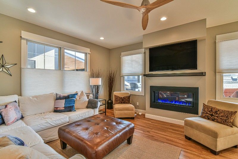 A living room with a couch , chairs , ottoman , fireplace and television.