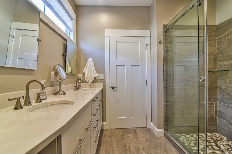 A bathroom with two sinks and a walk in shower.