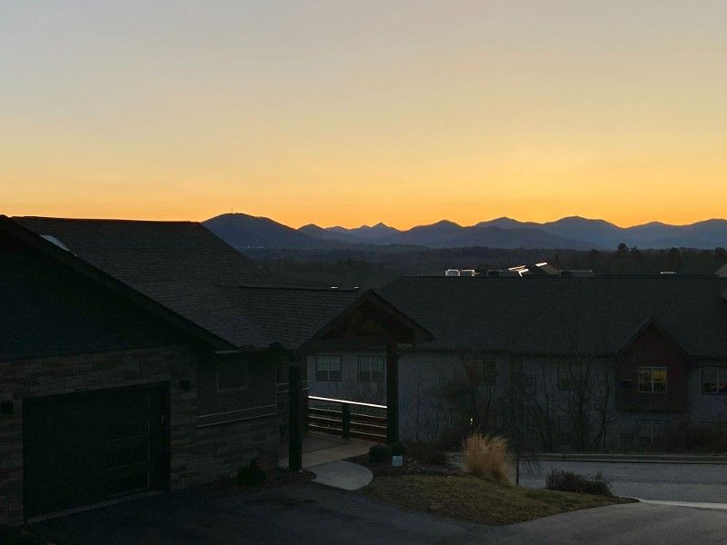 A sunset over a residential area with mountains in the background