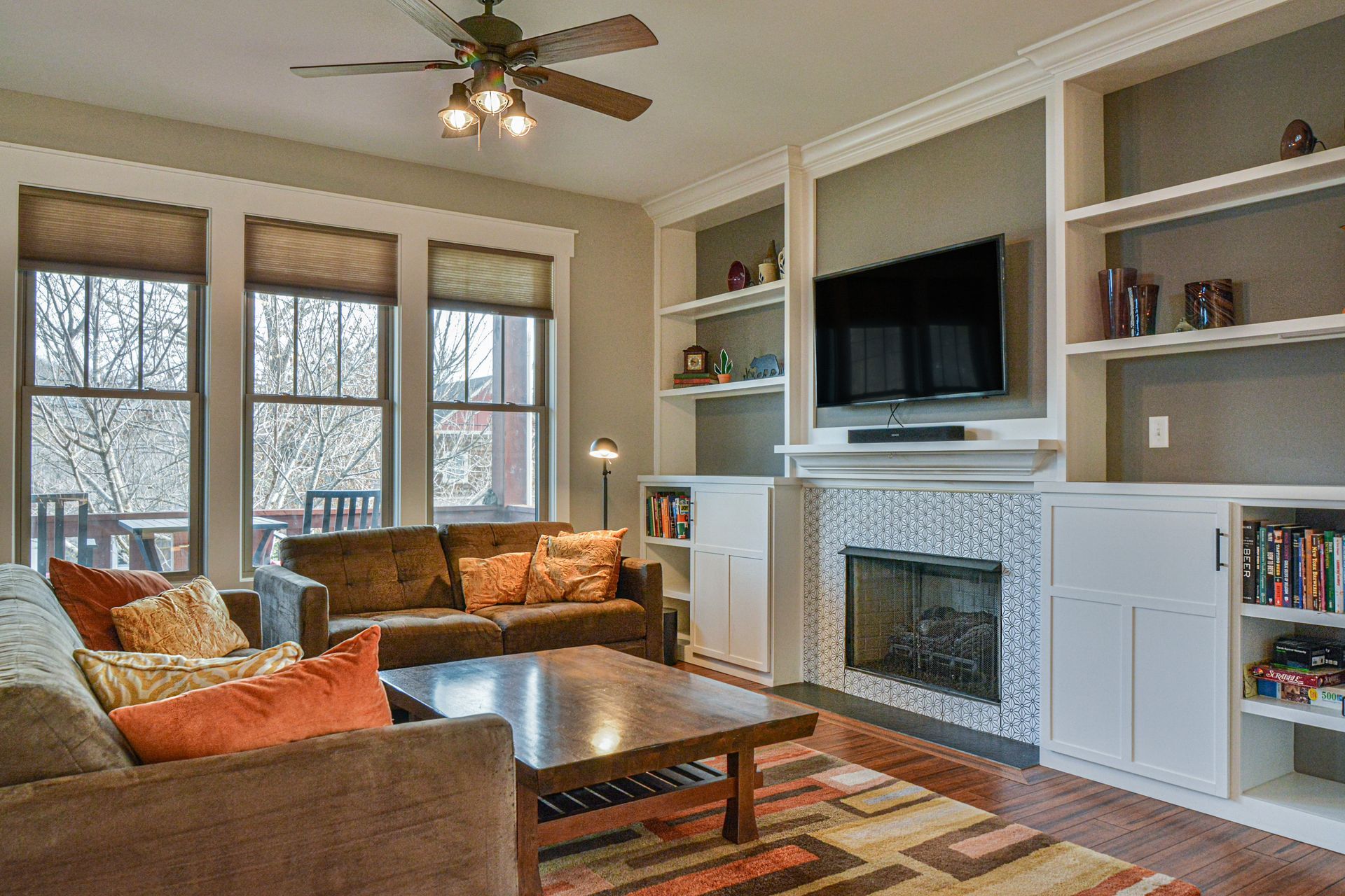 Cozy living room with brown sofas, a wooden coffee table, and a fireplace with built-in bookshelves and a TV above.