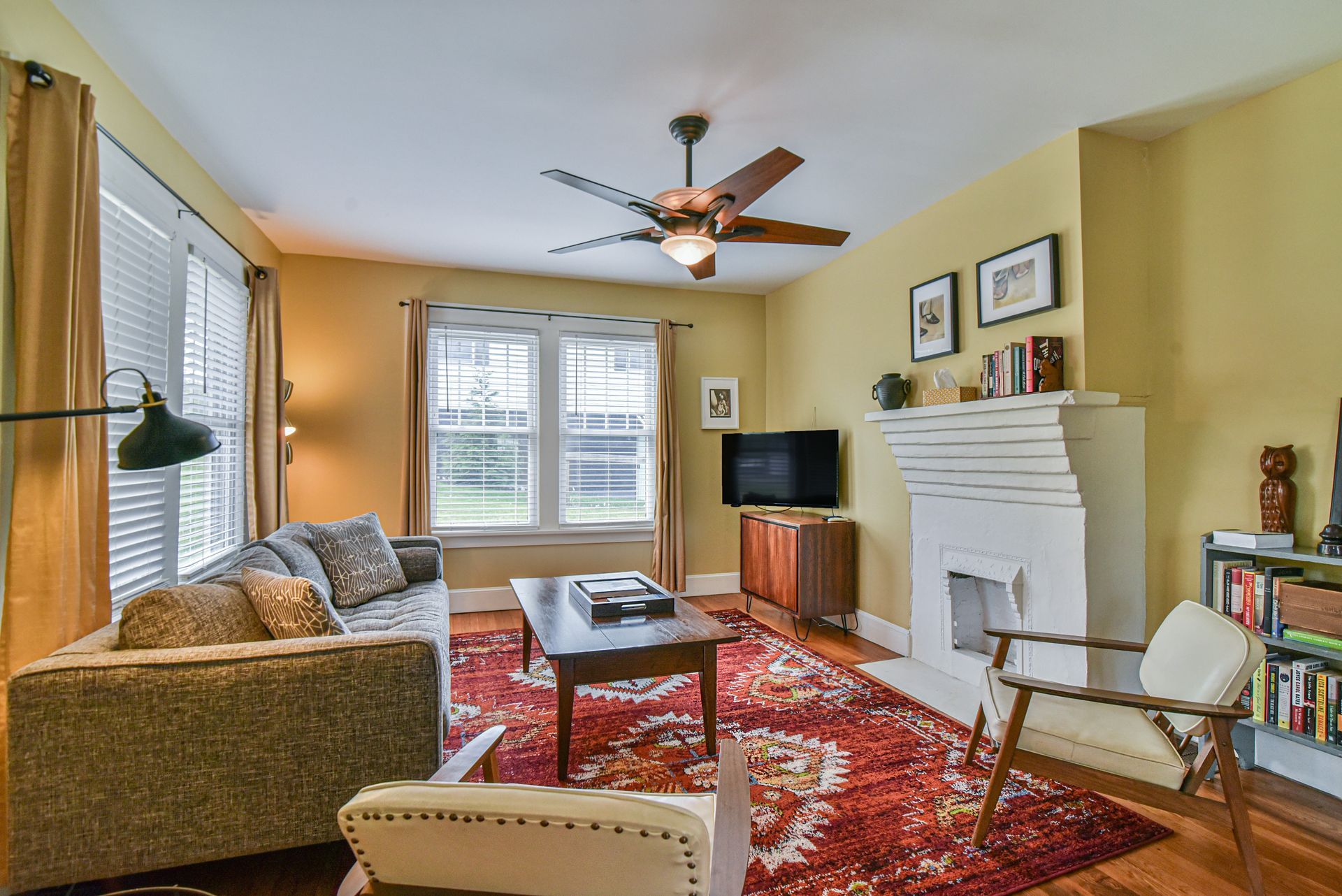 Cozy living room with patterned rug, fireplace, sofa, TV, and large window seating area