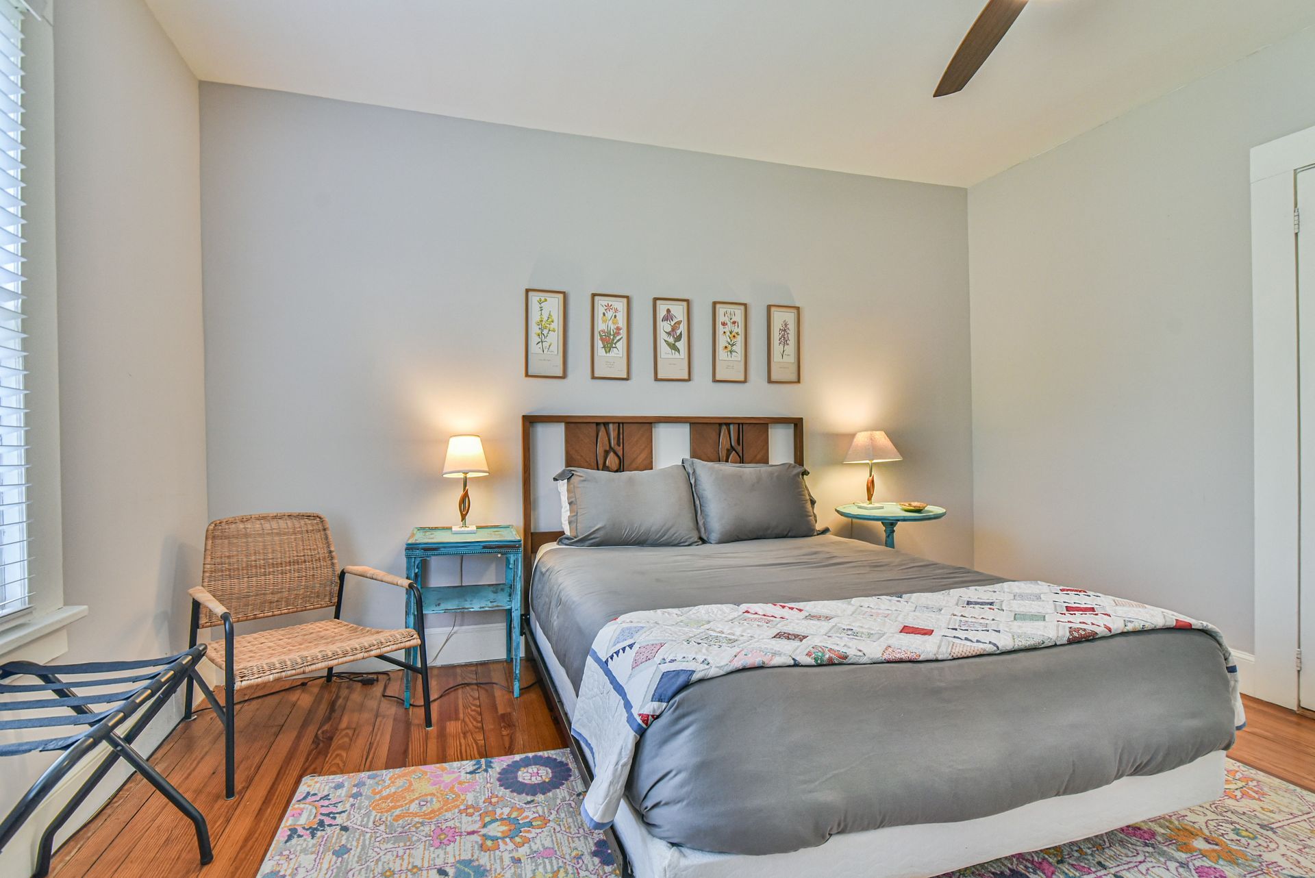 Cozy bedroom with a neatly made bed, nightstands, lamps, chair, and framed art on the wall.
