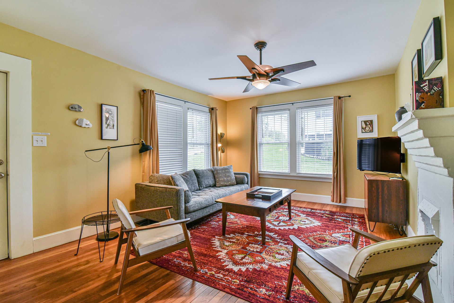 Bright living room with red rug, gray sofa, chairs, coffee table, and large windows