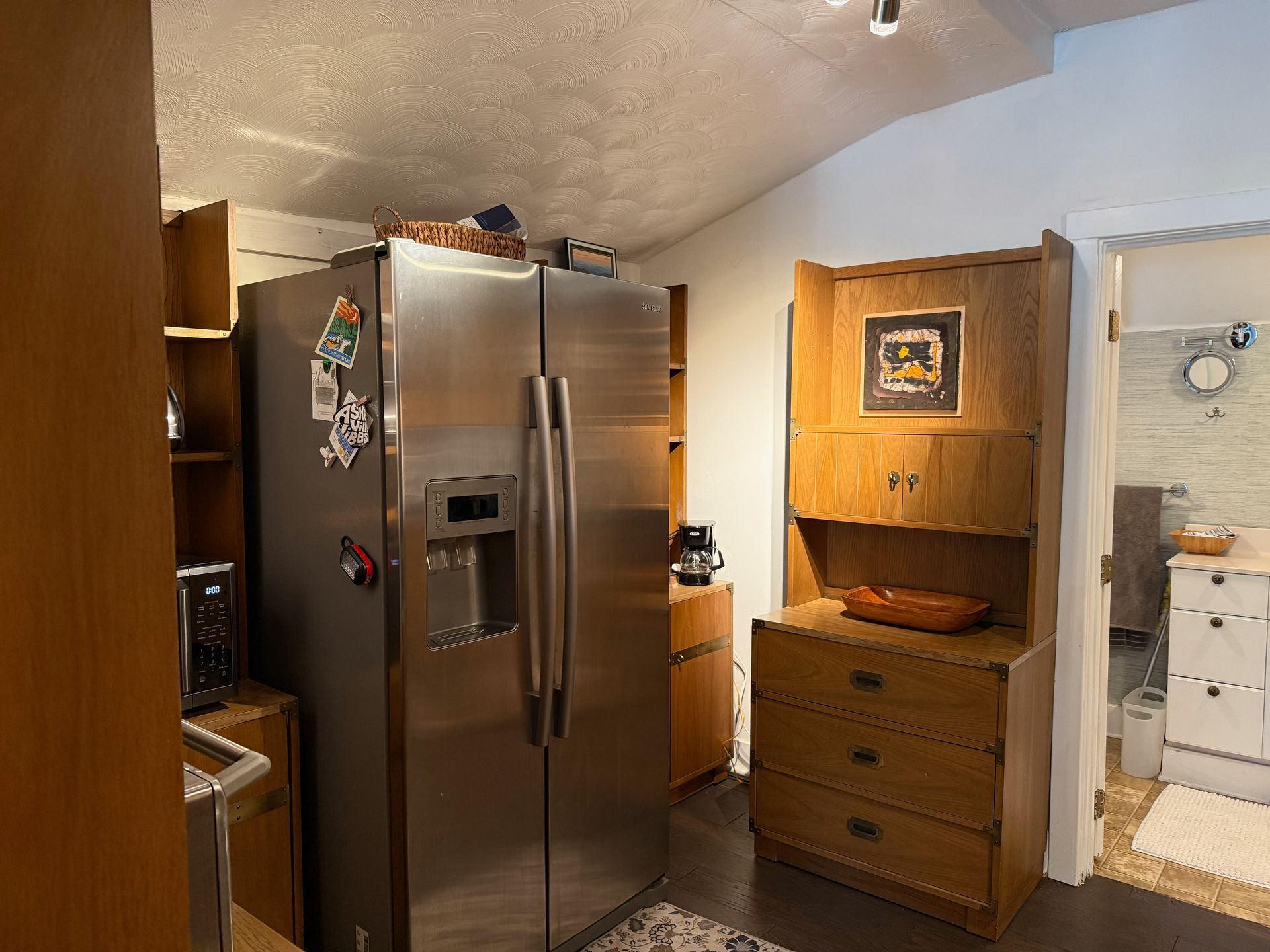 Kitchen with stainless steel refrigerator, wood cabinets, and a doorway to a laundry room.
