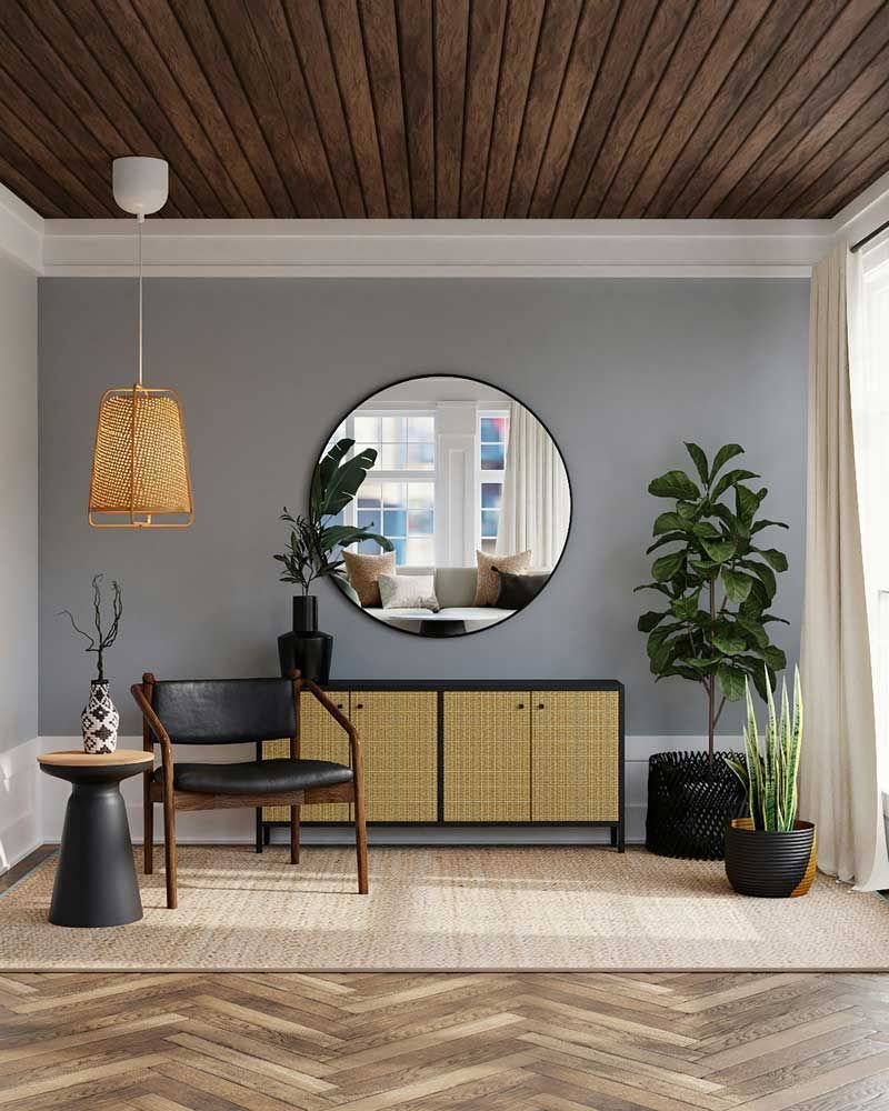 Modern living room with a round mirror, woven cabinet, wooden ceiling, plants, and black chair on a herringbone floor