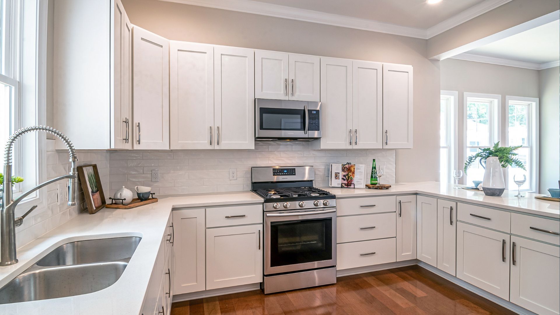 Bright white kitchen with cabinets, stainless appliances, sink, and hardwood floor
